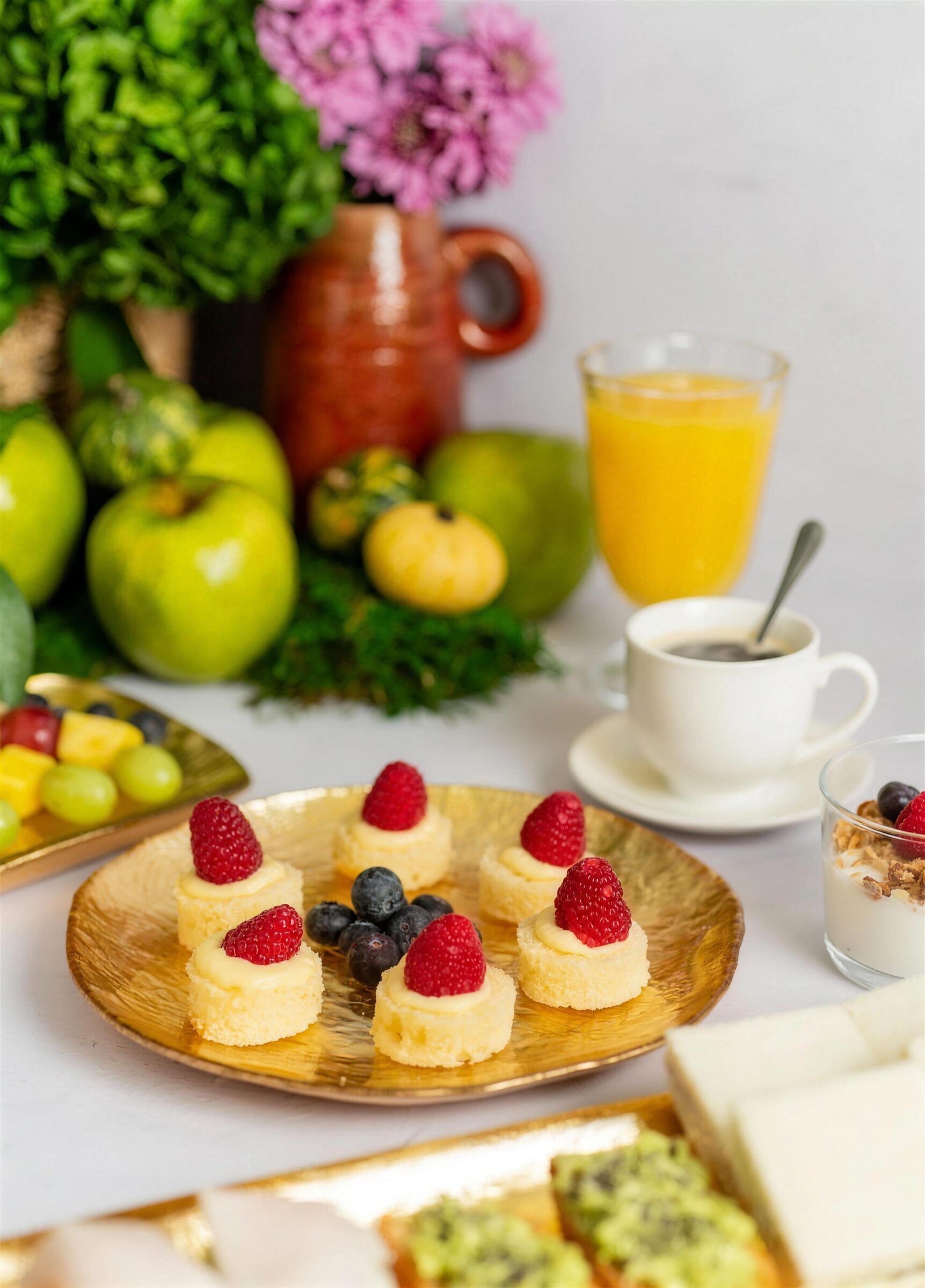 Mesa de desayuno de empresa con bizcochitos de frambuesa, zumo de naranja, café y yogur, catering María Lluch en Madrid