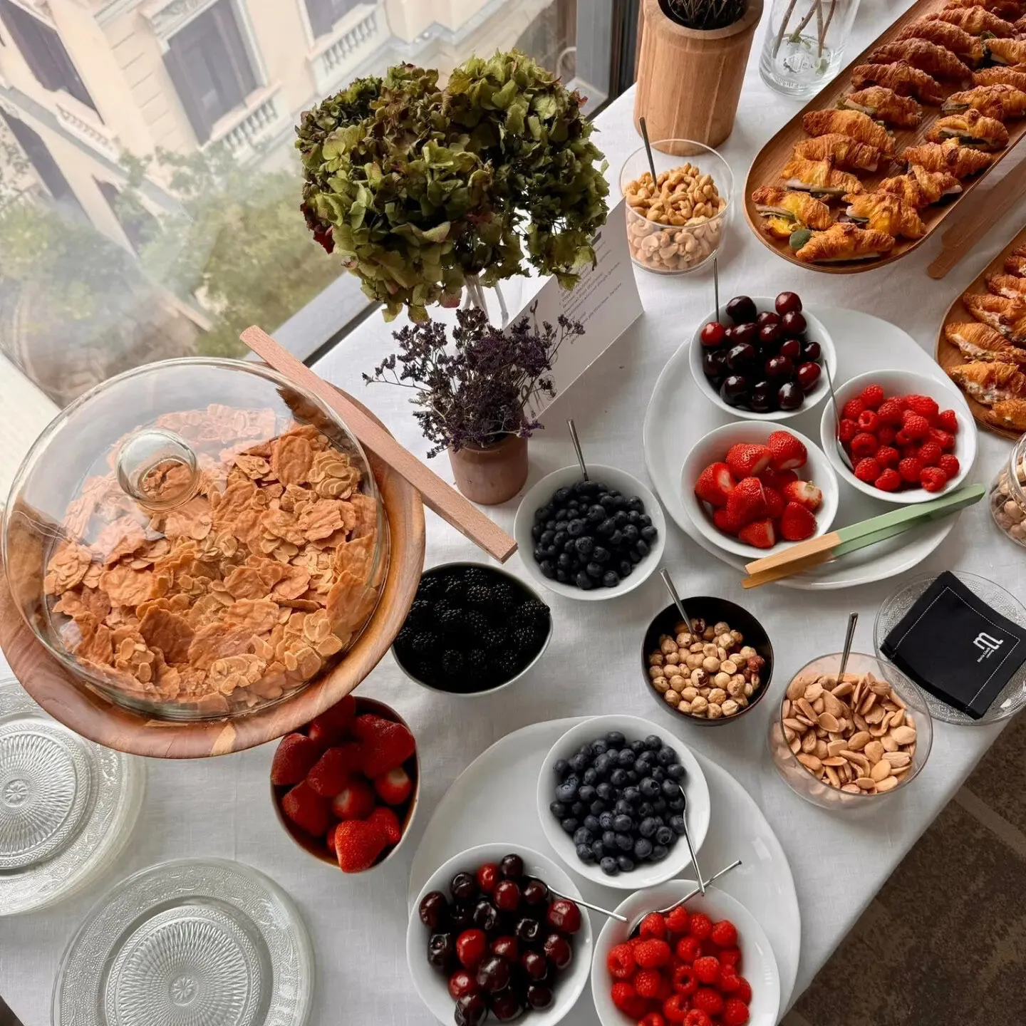 Overhead view of a breakfast table with red fruit, nuts and mini croissants, María Lluch catering in Madrid