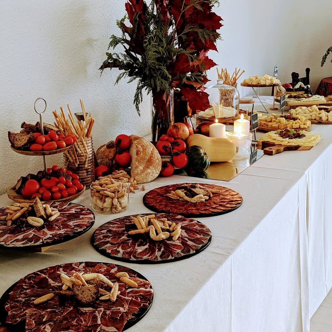 Buffet table with Iberian ham, cheeses, tomatoes and bread, with autumn decoration and candles, María Lluch catering in Madrid