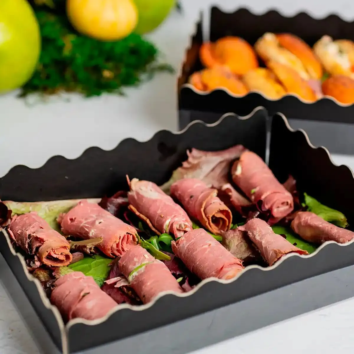 Rollitos de pastrami sobre ensalada en caja de catering para eventos, María Lluch Catering en Madrid